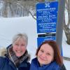 To kvinner foran blått skilt med severdighetstegn