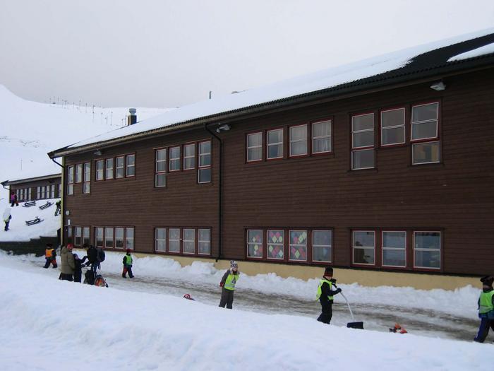 Barn som leker i snøen foran skolebygning - Klikk for stort bilde
