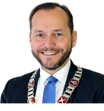 Portrettbilde av mann med kort hår og skjegg, iført dress med blått slips og ordførerkjede. - Klikk for stort bilde