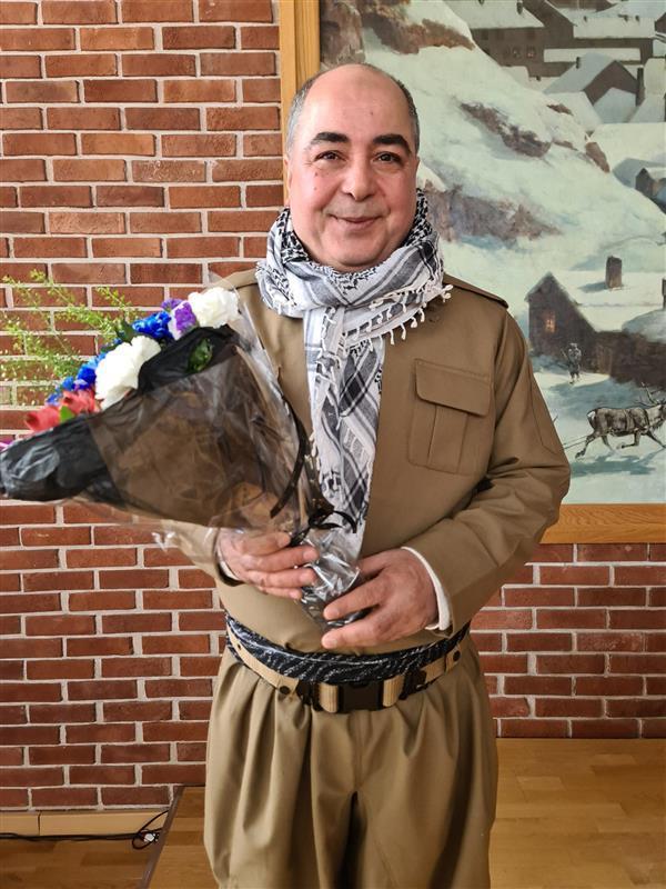 Mann med palestinaskjerf og blomsterbukett i kommunestyresalen  - Klikk for stort bilde