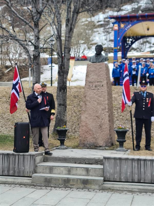Bysten av Ole Olsen. Mann i dress. Norske flagg. - Klikk for stort bilde