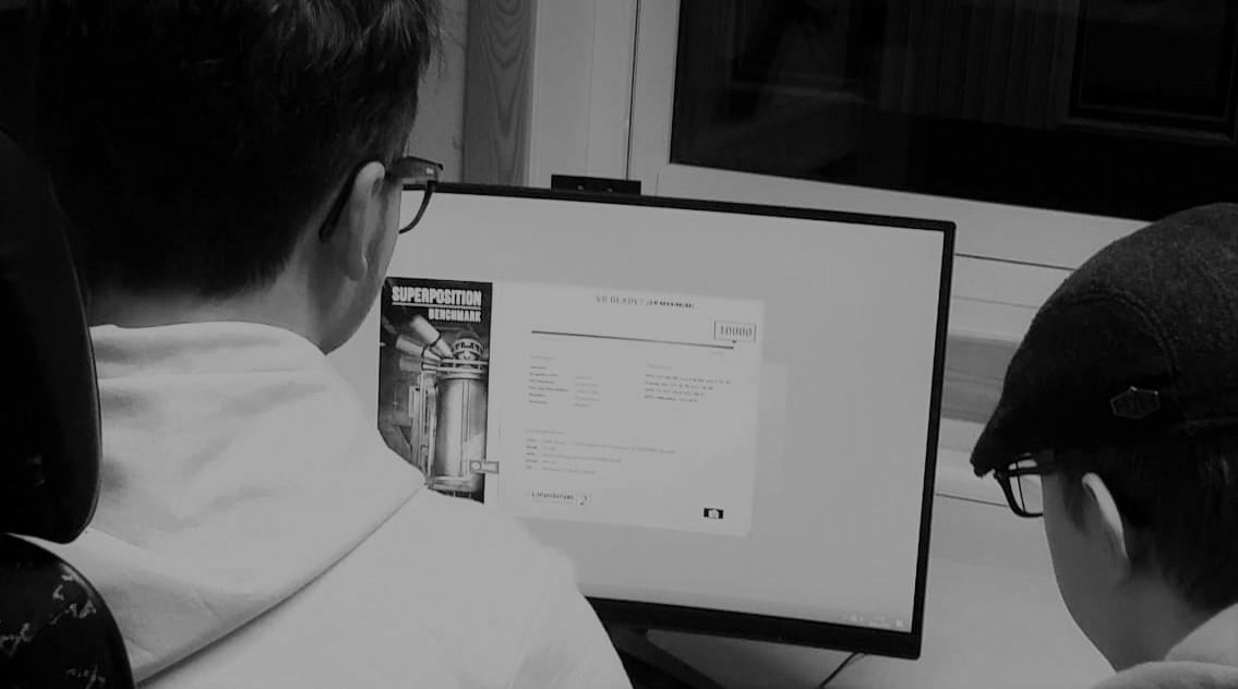 To personer sitter foran en dataskjerm i et klasserom eller verkstedmiljø og ser på et dokument og en plakat som er åpnet på skjermen. - Klikk for stort bilde